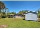 Spacious backyard featuring lush lawn, mature trees, and a storage shed, offering ample space for outdoor activities at 6181 Jack St, Venice, FL 34293
