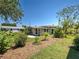 Charming backyard featuring lush grass, mature trees, a cozy patio, and quaint exterior of the house at 6181 Jack St, Venice, FL 34293