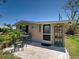 Exterior shot showcasing the house, a small patio with outdoor seating, and decorative shelving near the entrance at 6181 Jack St, Venice, FL 34293