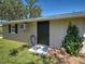 Home exterior featuring a dark door, window with black shutters, and manicured greenery at 6181 Jack St, Venice, FL 34293