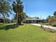 Charming single-story home featuring a lush green lawn, tropical palm trees, and a long driveway at 6181 Jack St, Venice, FL 34293