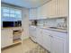 Functional kitchen with white cabinets, modern appliances, and neutral tile flooring at 6181 Jack St, Venice, FL 34293