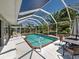 Enclosed pool area with a beautiful pool, adjacent outdoor seating, and tropical landscaping for privacy at 6181 Jack St, Venice, FL 34293