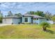 Charming single-story home with a well-manicured lawn and a two-car garage, complemented by lush landscaping at 7108 Harle Ave, North Port, FL 34291