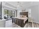 Bright main bedroom with tray ceiling, fan, wood-look floors, and sliding door access to the outdoor space at 7108 Harle Ave, North Port, FL 34291
