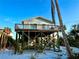 Charming coastal home on stilts with light blue siding and a cozy balcony, surrounded by lush tropical vegetation at 8714 King St, Placida, FL 33946