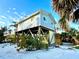 Coastal home on stilts with light blue siding, featuring a sturdy design and surrounded by tropical plants at 8714 King St, Placida, FL 33946