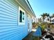 Charming beach house showcasing a bright blue exterior, wooden deck, and swaying palm trees against a clear sky at 8714 King St, Placida, FL 33946