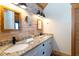 Well-lit bathroom featuring double sinks, granite countertops, and a brick accent wall for added charm at 8812 Grand Ave, Placida, FL 33946