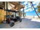 Golf cart parked under a beach house with a sandy yard and a path leading to the shore at 8812 Grand Ave, Placida, FL 33946