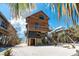 Gorgeous elevated beach house with wood siding, a balcony, and a sandy yard with palm trees at 8812 Grand Ave, Placida, FL 33946