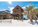 Beach house featuring rustic wood facade, elevated construction, and convenient ground-level lounge area with Adirondack chairs at 8812 Grand Ave, Placida, FL 33946