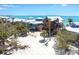 Charming beachfront home featuring a rustic wood exterior and elevated construction, surrounded by sandy dunes and palm trees at 8812 Grand Ave, Placida, FL 33946