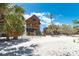 View of elevated beach house with wood siding, a balcony, and a sandy yard with palm trees at 8812 Grand Ave, Placida, FL 33946