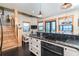 A kitchen area with white cabinets, stainless steel appliances, black countertop and stairs leading up to the next level at 8812 Grand Ave, Placida, FL 33946