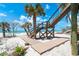 Wooden beach access walkway leading to steps, complemented by palm trees and views of the clear turquoise ocean at 8812 Grand Ave, Placida, FL 33946