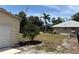 Well-maintained backyard featuring a screened-in lanai and storage shed, surrounded by lush landscaping and palm trees at 941 Elwood Ave, Englewood, FL 34223