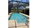 Sparkling in-ground pool enclosed with a screened lanai, surrounded by brick pavers, offering a private outdoor retreat at 941 Elwood Ave, Englewood, FL 34223