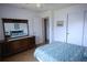 Bright bedroom with a light blue bedspread, wooden floors, and a lovely wood dresser with mirror at 10275 Euston Ave, Englewood, FL 34224