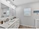 Bright bathroom featuring dual sinks, modern faucets, a large mirror, and custom lighting at 10500 Sherman St, Englewood, FL 34224