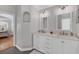 Bathroom featuring dual sinks with chrome fixtures, white cabinets and decorative lighting at 10500 Sherman St, Englewood, FL 34224