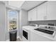 Bright laundry room with front-loading washer and dryer, storage, and outside view at 10500 Sherman St, Englewood, FL 34224