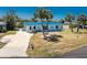Charming coastal home featuring a blue roof, palm trees, and a well-maintained lawn at 1167 Delmar St, Englewood, FL 34224