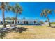Charming single-story home with a blue roof, palm trees, and a well-maintained lawn at 1167 Delmar St, Englewood, FL 34224