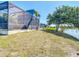 View of backyard, pool, and screened-in lanai with a canal in the background at 1167 Rotonda Cir, Rotonda West, FL 33947