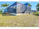 View of backyard, pool, and screened-in lanai with a canal in the background at 1167 Rotonda Cir, Rotonda West, FL 33947