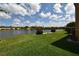Lakeside backyard with green lawn, lush bushes, and community townhomes under a partly cloudy blue sky at 11750 Tempest Harbor Loop, Venice, FL 34292