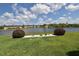 Scenic view of lake with manicured lawn and landscaping in backyard of community townhomes under bright sky at 11750 Tempest Harbor Loop, Venice, FL 34292
