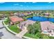 Beautiful aerial view of a home with well-maintained landscaping, a paver driveway, and lake views on a clear day at 13335 Golf Pointe Dr, Port Charlotte, FL 33953