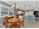 Open-concept dining area with chandelier, and a view of the kitchen with white cabinets and a breakfast bar at 13335 Golf Pointe Dr, Port Charlotte, FL 33953