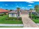 Charming single-story home featuring lush landscaping, a stone driveway, and a neutral color palette at 13335 Golf Pointe Dr, Port Charlotte, FL 33953