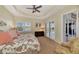 Bright main bedroom with tray ceiling, ceiling fan, and plantation shutters, leading to the lanai at 13335 Golf Pointe Dr, Port Charlotte, FL 33953