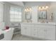Bright bathroom showcasing a dual sink vanity with cabinets and a soaking tub at 1400 Beach Rd # 2, Englewood, FL 34223