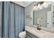 Updated bathroom featuring a stylish vanity, large mirror, and a shower with a blue curtain at 14454 Worthwhile Rd, Port Charlotte, FL 33953