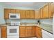 Well-equipped kitchen featuring wood cabinets, granite countertops, and modern white appliances at 14454 Worthwhile Rd, Port Charlotte, FL 33953