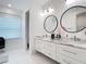 Contemporary bathroom with double vanity, marble counters, dual round mirrors, and large format tile at 16 Pine Valley Ct, Rotonda West, FL 33947