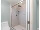 Modern tiled shower with glass door, rainfall showerhead, and white fixtures, in neutral toned bathroom at 2140 Carnac St, Port Charlotte, FL 33952
