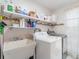 Functional laundry room equipped with washer, dryer, utility sink, and storage shelves at 2140 Carnac St, Port Charlotte, FL 33952