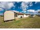 Rear view of the house showing the large backyard, shed, RV parking, and exterior details at 23347 Lehigh Ave, Port Charlotte, FL 33954