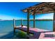 Waterfront home featuring a private covered dock with bench seating and scenic water views under a clear blue sky at 2450 N Beach Rd # 231, Englewood, FL 34223