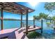 Waterfront home featuring a private covered dock with bench seating and scenic water views under a clear blue sky at 2450 N Beach Rd # 231, Englewood, FL 34223