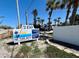Sunburst Condominiums sign displaying property address surrounded by palm trees in a sunny location at 2450 N Beach Rd # 231, Englewood, FL 34223