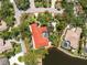 Stunning aerial view showcases the red-roofed home's well-maintained landscaping, screened-in pool, and serene lake frontage at 26 Saint Croix Way, Englewood, FL 34223