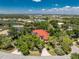 Aerial shot of a lake view house with a red roof, screened-in pool, circular driveway and mature trees on a large lot at 26 Saint Croix Way, Englewood, FL 34223