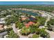 Aerial view of a red-roofed house with a lake view surrounded by trees and other upscale homes in the neighborhood at 26 Saint Croix Way, Englewood, FL 34223