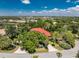 Picturesque aerial view of a lake view house with a red roof, screened-in pool, a circular driveway and mature landscaping at 26 Saint Croix Way, Englewood, FL 34223